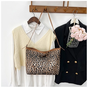 Dettaglio della borsa tote con stampa leopardata e finiture in pelle marrone appesa al muro