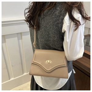 Dettaglio della borsa a busta beige con chiusura a rotazione ovale dorata in pelle fine