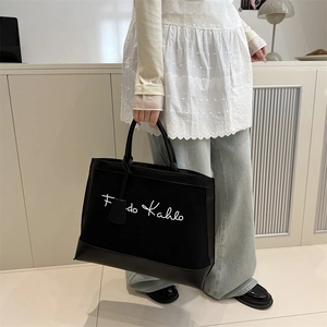 Chic black canvas tote bag with Frida Kahlo embroidery and leather trim