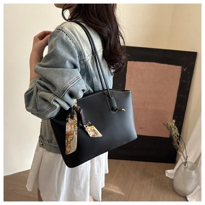 Dettaglio di una borsa tote nera con foulard di seta vintage sul sottile manico in pelle