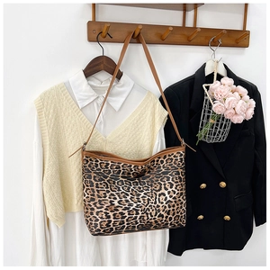 Dettaglio borsa shopper leopardata con tracolle in pelle marrone appesa a un supporto