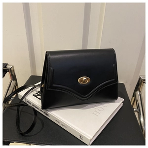 Dettaglio borsa sottobraccio in pelle nera con chiusura a scatto ovale dorata ed elegante