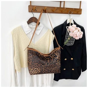 Dettaglio della borsa tote leopardata con manici in pelle marrone appesa nell'armadio
