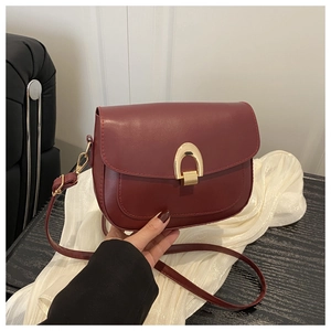 Detail shot of a wine red crescent flap bag featuring a golden horseshoe metal lock buckle