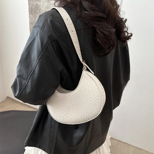 Creamy white crescent handbag with crocodile embossing on adjustable shoulder strap