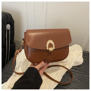 Detail of vintage brown leather saddle bag with distinctive gold U-shaped metal buckle