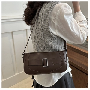 Detail of dark brown leather underarm bag with silver buckle worn by a model