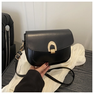 Close-up of black matte saddle bag featuring a distinctive gold arched metal clasp