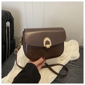 Detailed view of dark brown leather saddle bag featuring a textured U-shaped gold metal clasp