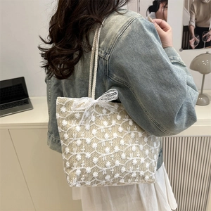Sac fourre-tout tissé beige avec broderie florale en dentelle et nœud porté par mannequin