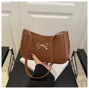 Gros plan sur le sac en cuir caramel avec boucle en métal doré en forme de nœud
