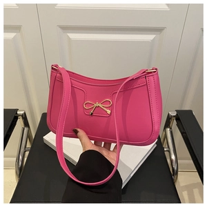 Détail d'un sac à bandoulière magenta avec une boucle décorative en nœud doré élégant