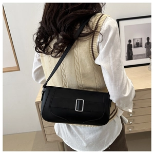 Rear view of a chic black crescent underarm bag with silver buckle on a beige vest