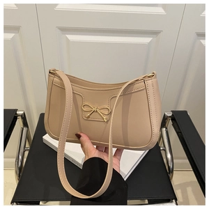 Détail du sac beige avec boucle noeud dorée et texture de couture en cuir raffiné