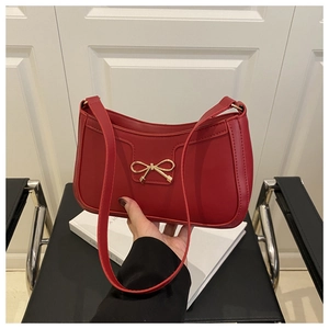 Détail du sac sous le bras en cuir rouge avec boucle dorée en nœud et coutures fines