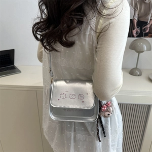 Metallic silver crossbody bag with cute bear prints and plush charm shown on model