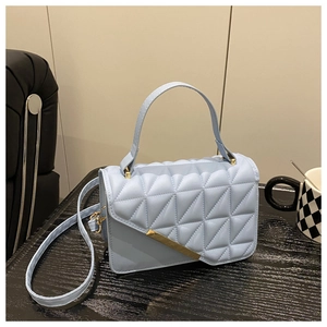 Detail of light blue quilted leather handbag with asymmetric flap and gold metal trim