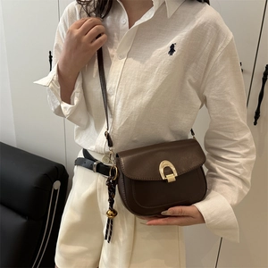 Brown leather saddle bag with gold horseshoe buckle and adjustable crossbody shoulder strap