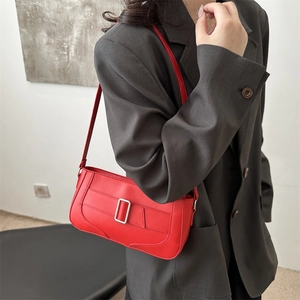 Chic red leather crescent shoulder bag with silver buckle worn on grey blazer