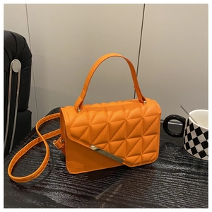 Detailed view of orange quilted shoulder bag with gold metal hardware and top handle