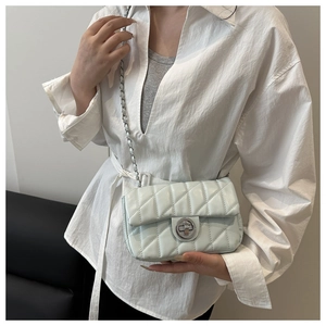 Detail of mint green quilted leather bag with silver metal turn-lock and chain strap