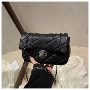 Detail of black quilted crossbody bag with silver metal swivel lock and chain strap