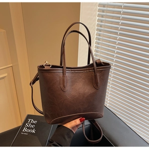 Close-up of dark brown leather tote bag with fine stitching and gold hardware detail