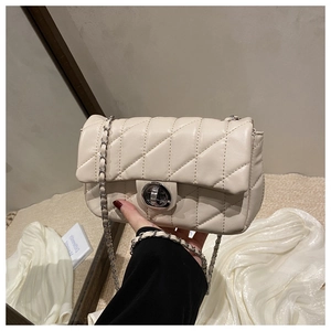 Close-up of beige quilted leather flap bag with silver chain and metal twist lock