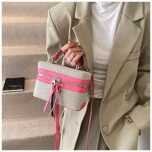 Detail of canvas box bag with pink leather trim and dual zip tassels on stone steps