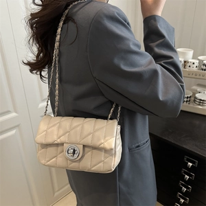 Elegant beige quilted crossbody bag with silver chain strap and metal swivel lock