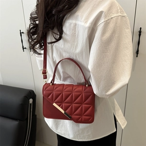 Deep red quilted leather crossbody bag with gold hardware shown on a model's shoulder