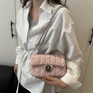 Pink quilted crossbody bag with chain strap and metal clasp shown on a female model
