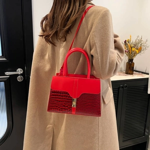 Red crossbody bag with crocodile embossed texture and gold lock shown on camel coat