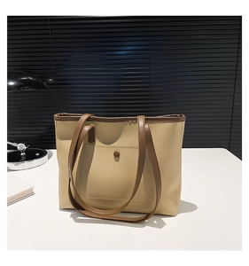 Close-up of beige tote bag with brown straps and front pocket detail on a desk