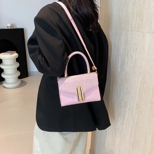 Pink leather shoulder bag with glitter flap shown in a stylish minimalist setting