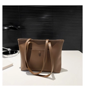 Detailed close-up of a brown leather tote bag featuring a practical front snap button pocket