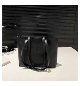 Minimalist black leather tote bag with functional snap pocket and long shoulder straps