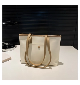 Close-up of minimalist cream tote bag with khaki trim and exterior buckle pocket detail