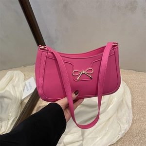 Sac à bandoulière rose avec nœud doré sur un fond élégant en tissu de soie