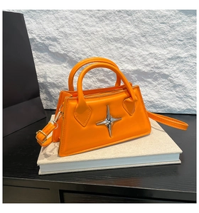 Detail der orangefarbenen Trapez-Handtasche mit silberner Sternschnalle im Minimal-Stil