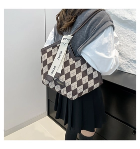 Detail of checkered tote bag with V-shaped opening and decorative logo straps