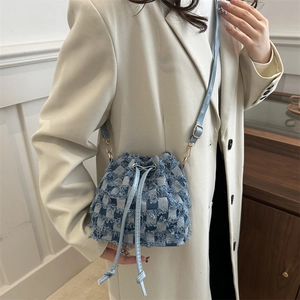 Blue denim checkerboard drawstring bucket bag worn with a stylish beige blazer