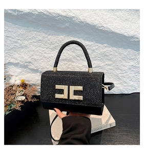 Detail der schwarzen Glitzertasche mit goldenem Logo und feinen Pailletten