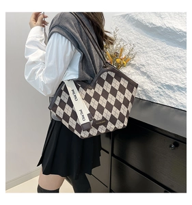 Close-up of brown checkerboard tote bag with fabric texture and decorative brand ribbon