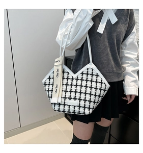 Close-up of black and white tweed tote bag with Chia'2nd charm shown on a shoulder