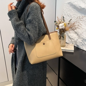 Minimalist beige PU leather tote bag with brown handles and front pocket shown on model