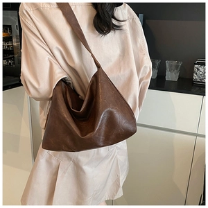 Side view of large vintage brown leather tote bag with wide strap and soft drape