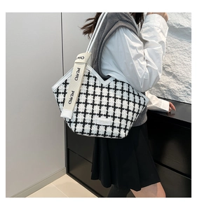 Detail of black and white tweed tote bag with shoulder strap and woven brand label