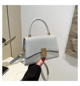 Dettaglio borsa a tracolla grigio chiaro con strass argento e chiusura a scatto oro