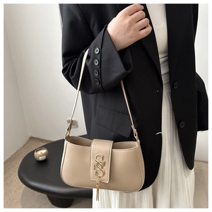 Detail of beige faux leather handbag featuring a gold interlocking S buckle and tassel